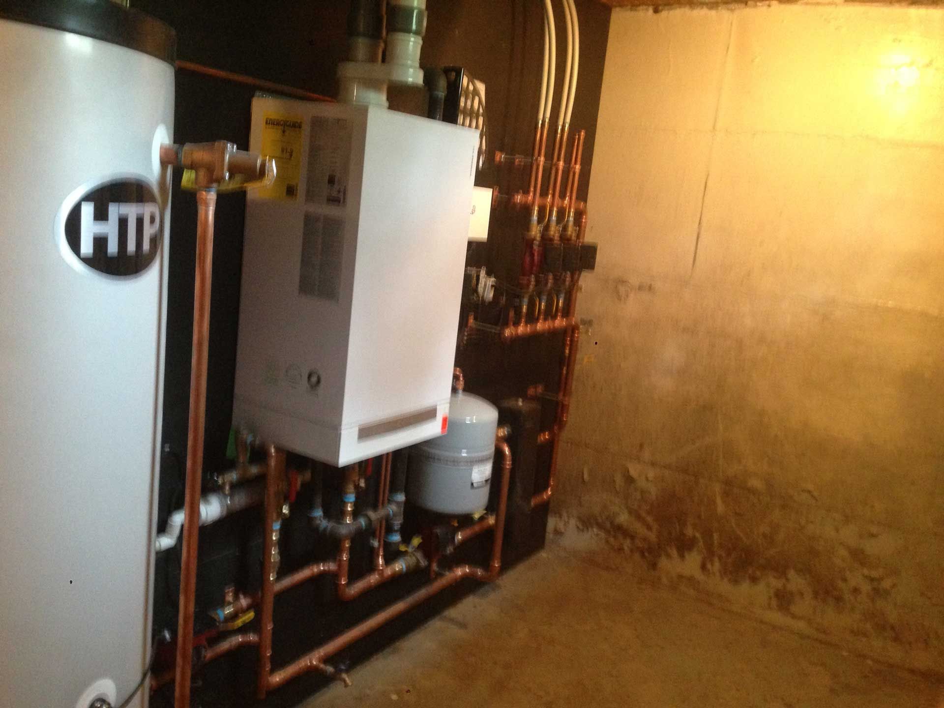Water heater and boiler system in basement with copper pipes.
