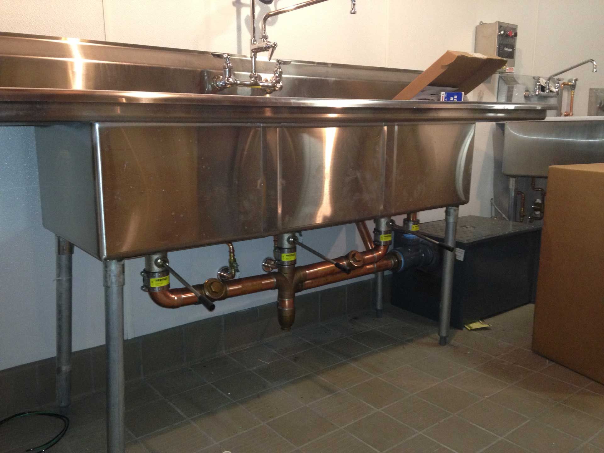 Plumber in blue overalls connecting white plastic pipe fittings, indoor setting.