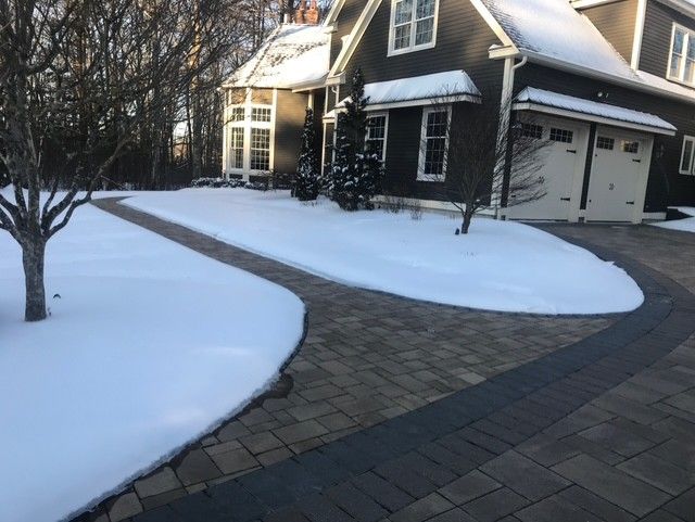 Snowy walkway leads to a dark house with a white garage. Winter scene.