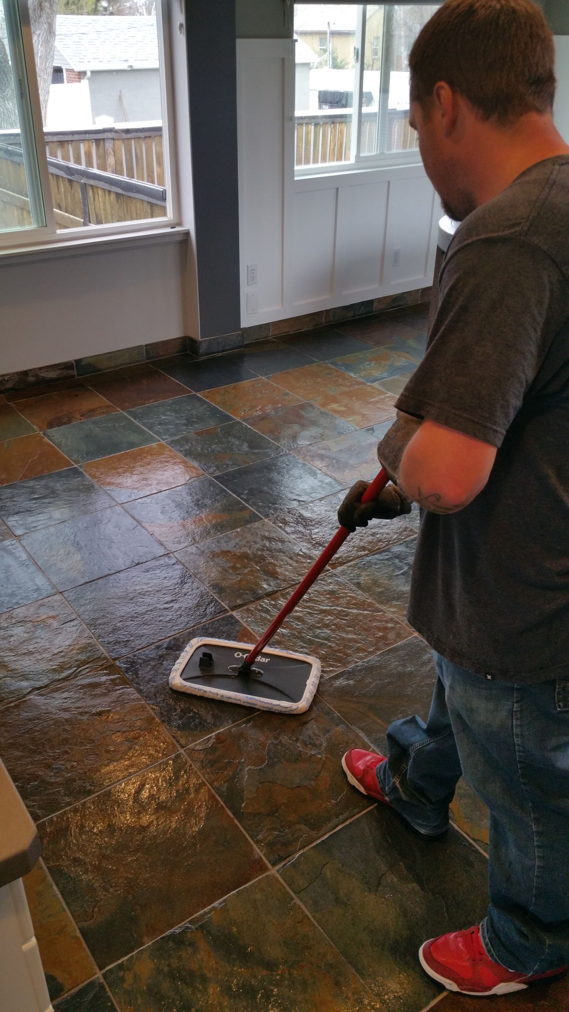 A man is cleaning a tile floor with a mop.
