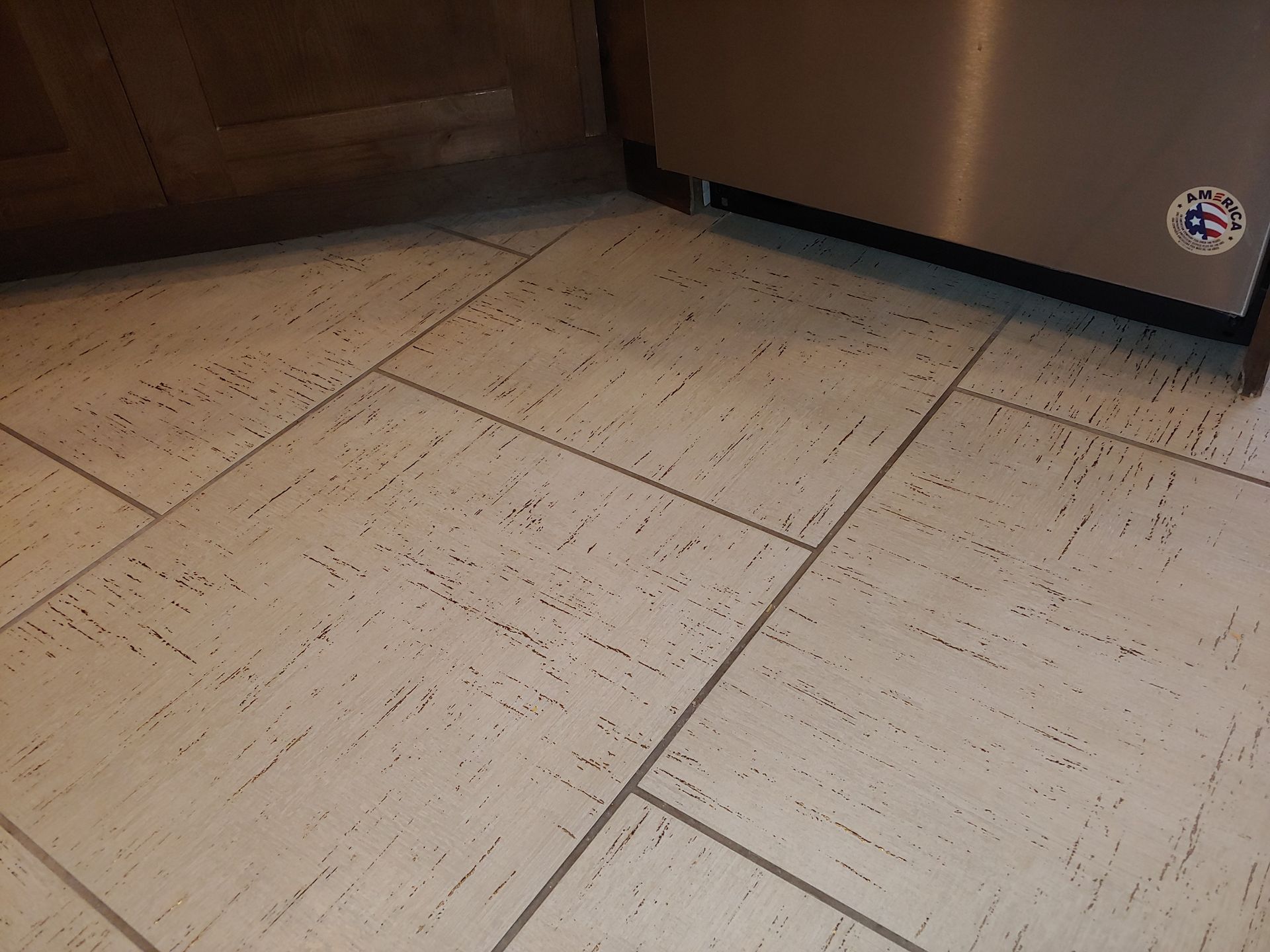A stainless steel dishwasher is sitting next to a tiled floor in a kitchen.