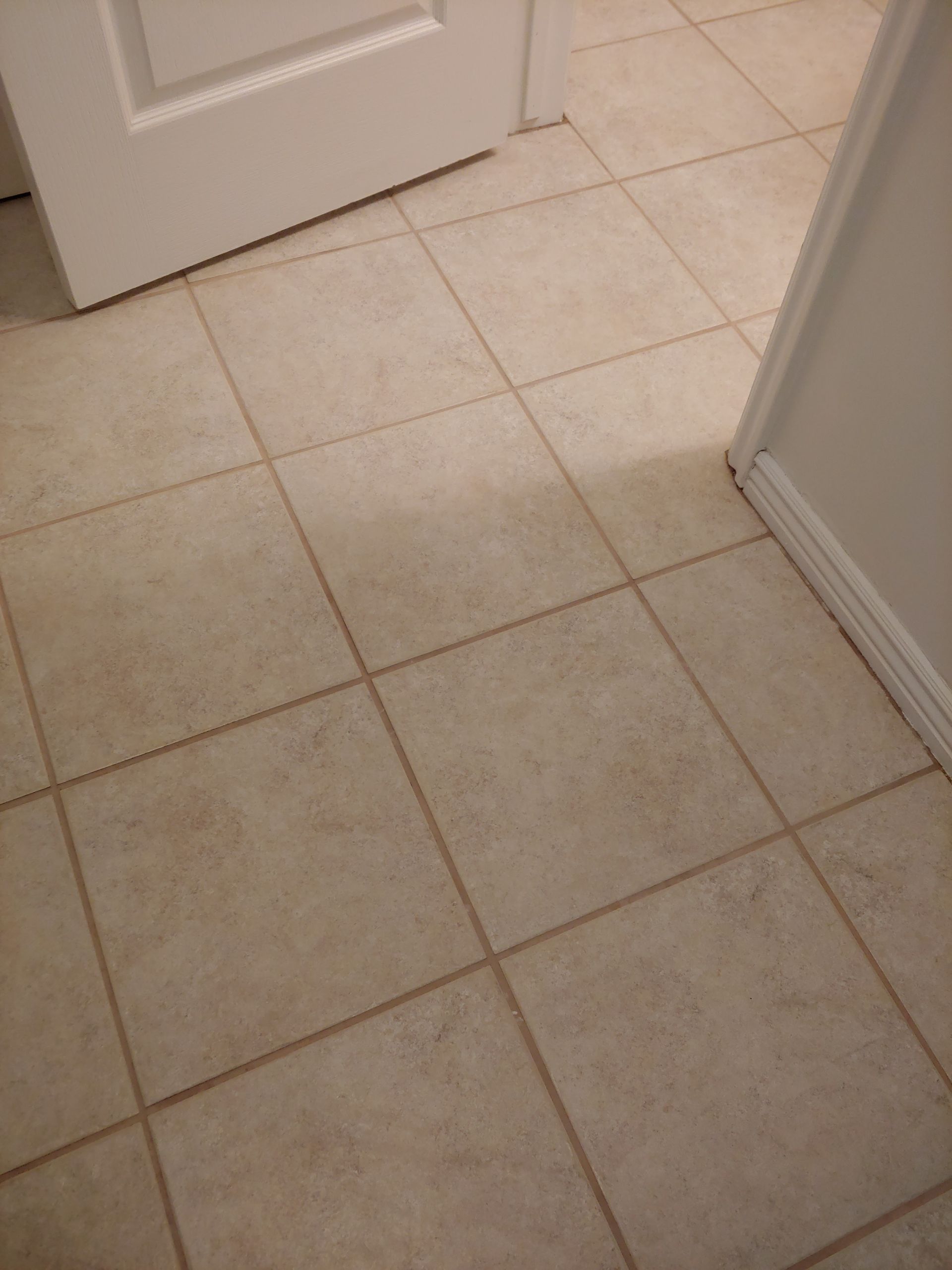 A tiled floor with a white door in the background