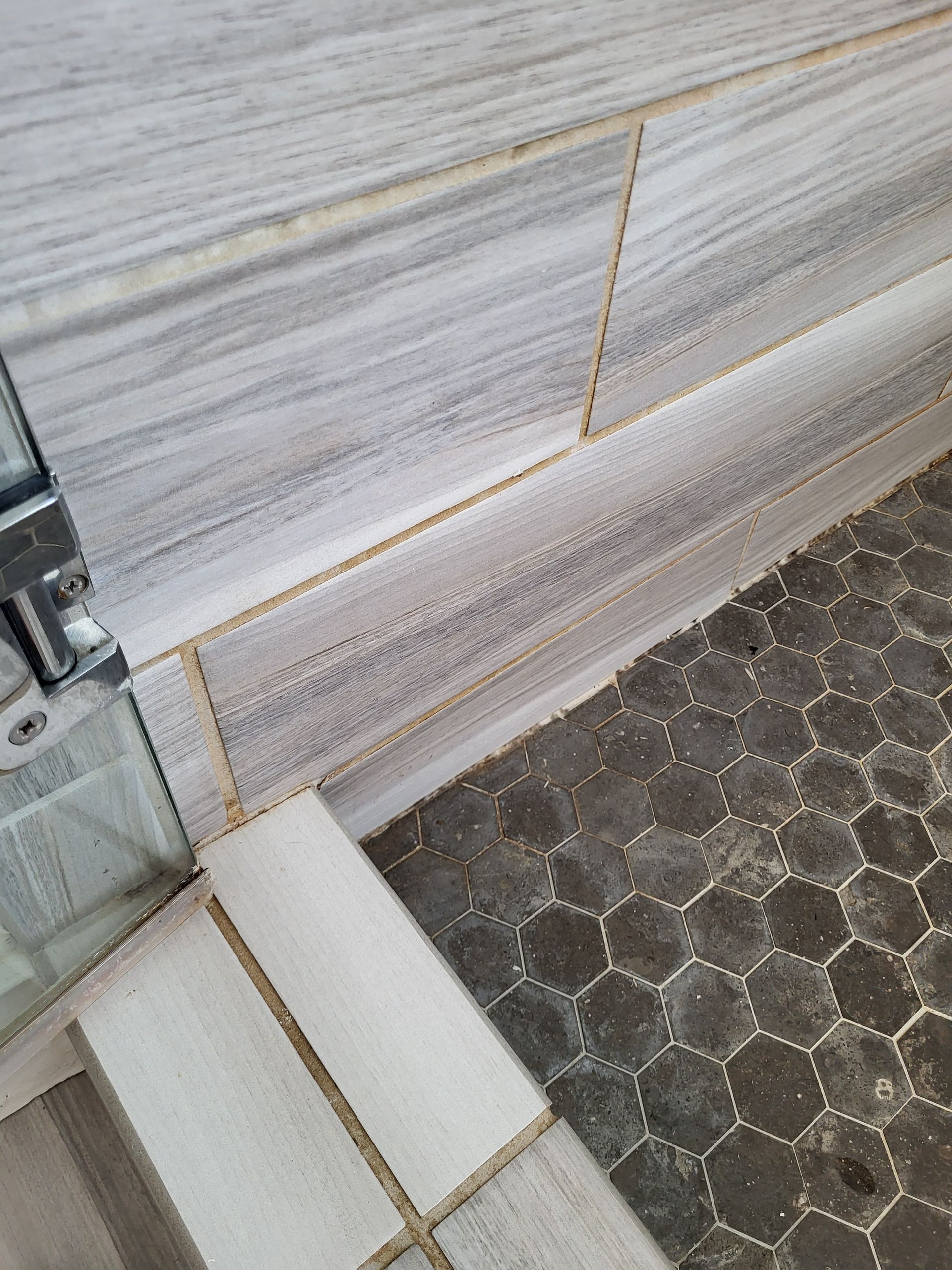 A close up of a tiled wall and floor in a bathroom.
