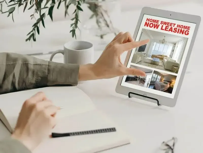 a close up image of a pair of hands on a table, zooming in on details of an apartment rental ad on a tablet