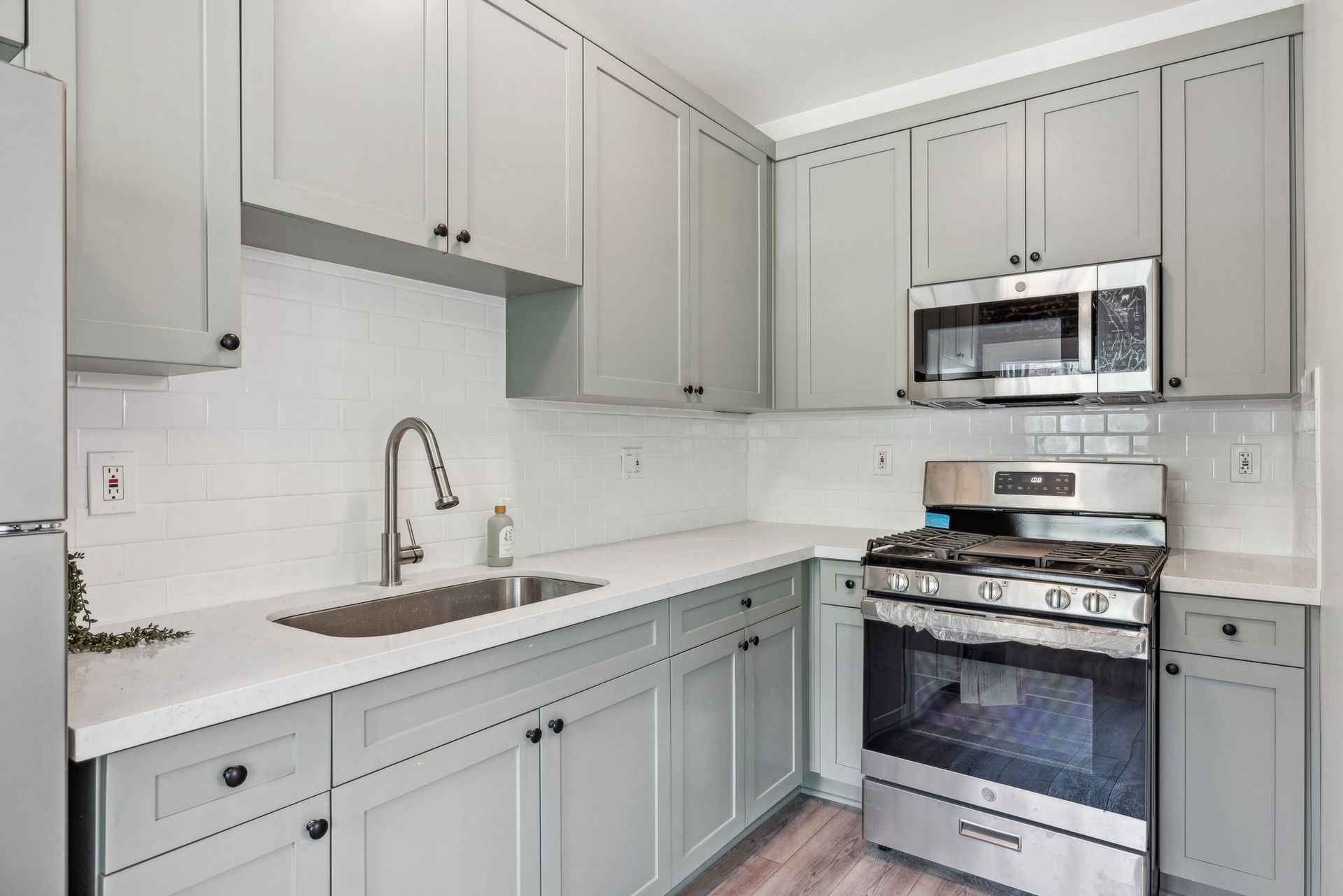 interior photo of the Ansley apartment units showing the kitchen with stove, sink, cabinet and stainless refrigerator