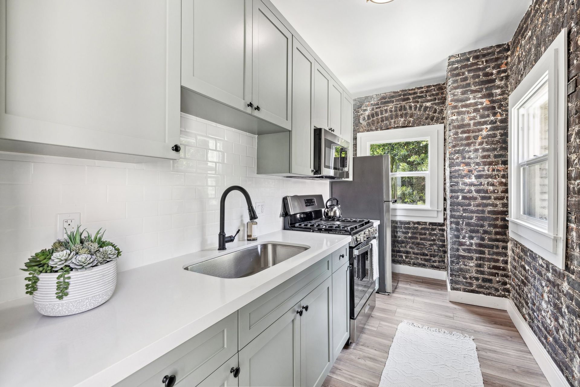 A kitchen with white cabinets and a brick wall. Rental Property Management Company in Toluca Lake, Sky Properties, Inc.