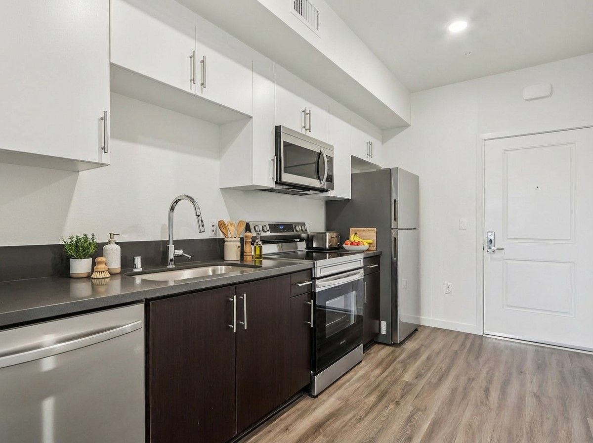 photo of The Centennial's cozy and bright bedroom with a bed, side table and windows with opened blinds