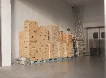 Stacks of boxes inside a storage sapce with white walll as an extra space to lease out