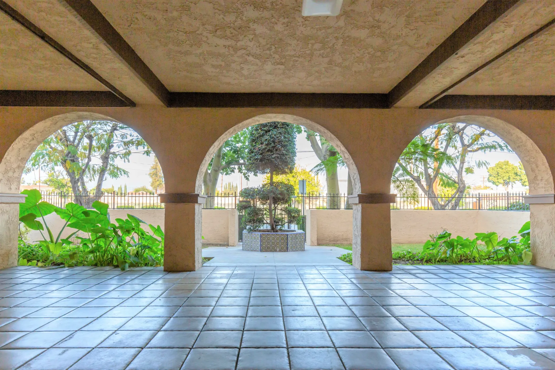 image of a covered deck with curved arch columns in tiles and recessed ceiling leading to the courtyard garden