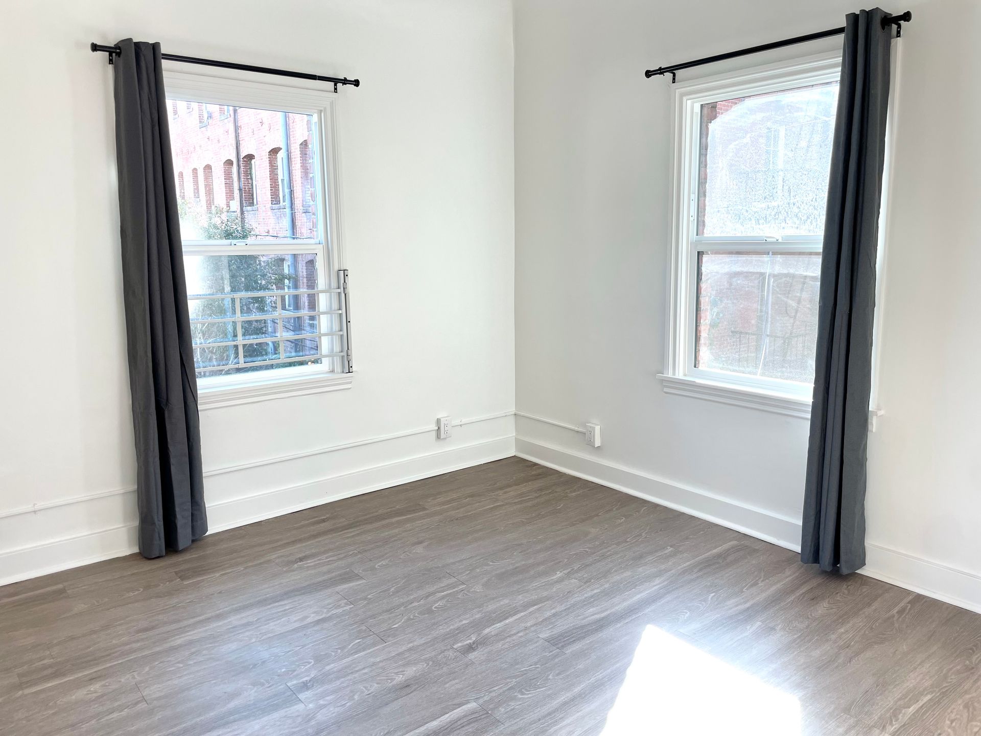 Interior photo of the Ansley Apartments, showing 2 huge windows with curtains and lots of natural light
