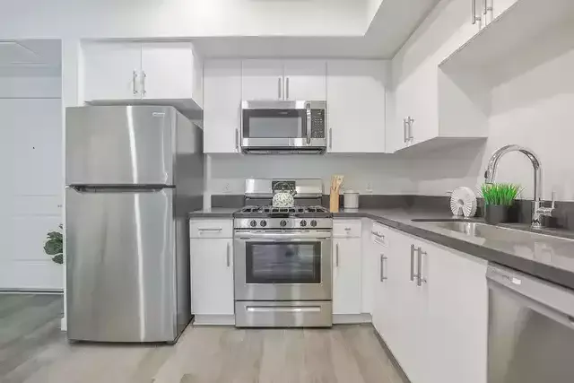 photo of The Centennial's modern kitchen showing a stainless steel refrigerator, range oven, microwave, and sink