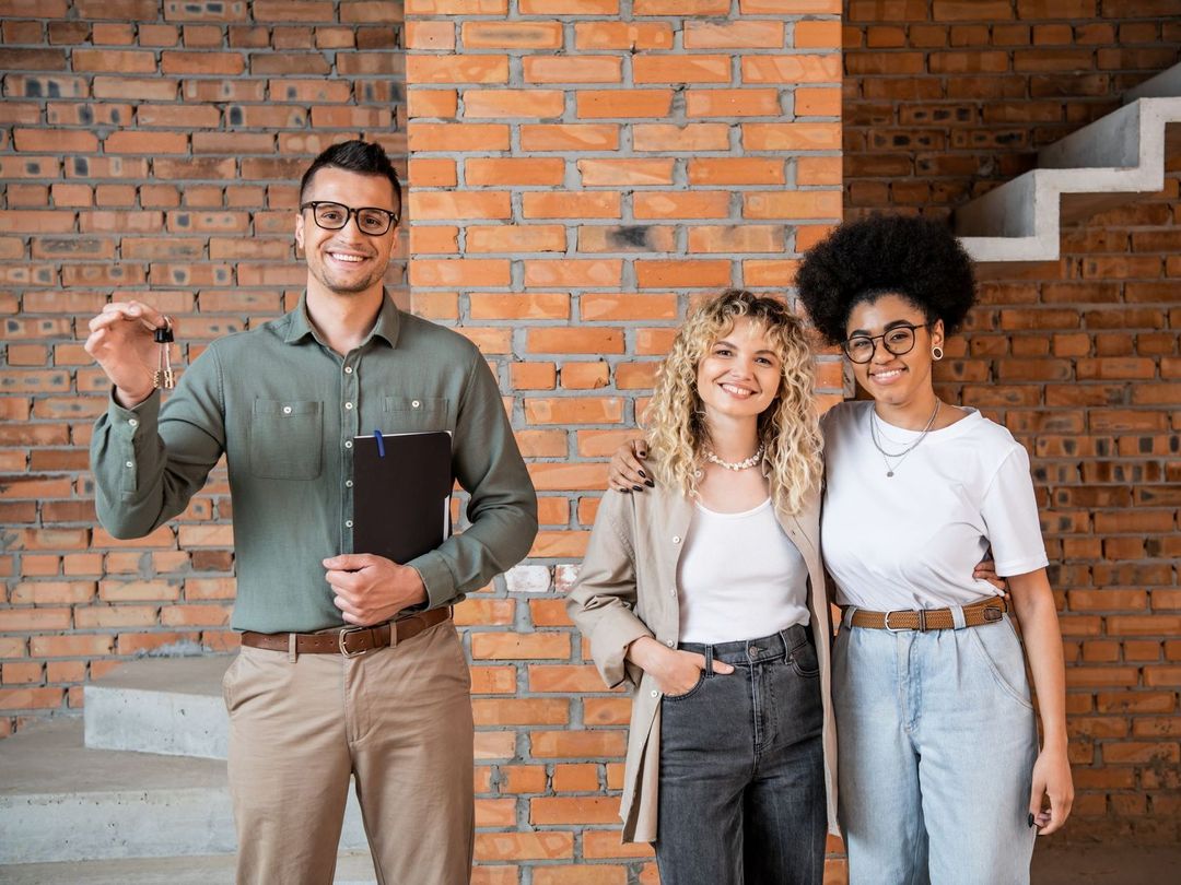 A group of people are standing next to each other in front of a brick wall.