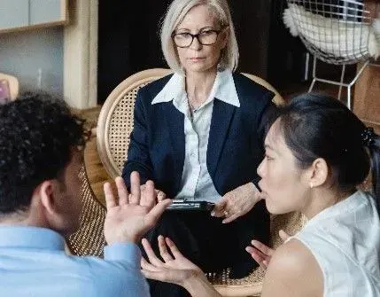 close-up photo of 2 tenants with hand gestures shown in a discussion with a manager in the middle mediating