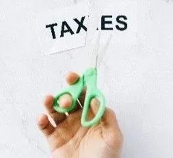 A Hand holding a scissor cutting the word tax es into half signifying need to have tax assessed