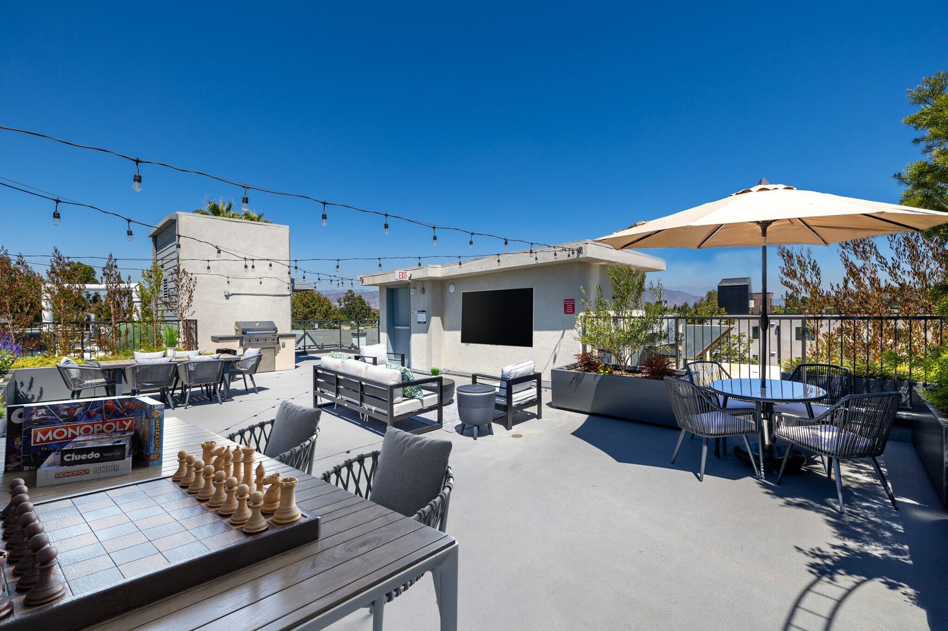 Photo showing an the Mix Luxury Apartment rooftop showing the outdoor barbecue, roof top tables and lovely plants
