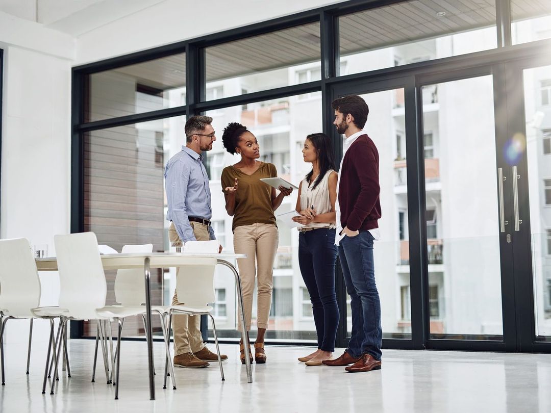 A group of people are standing in a room talking to each other.
