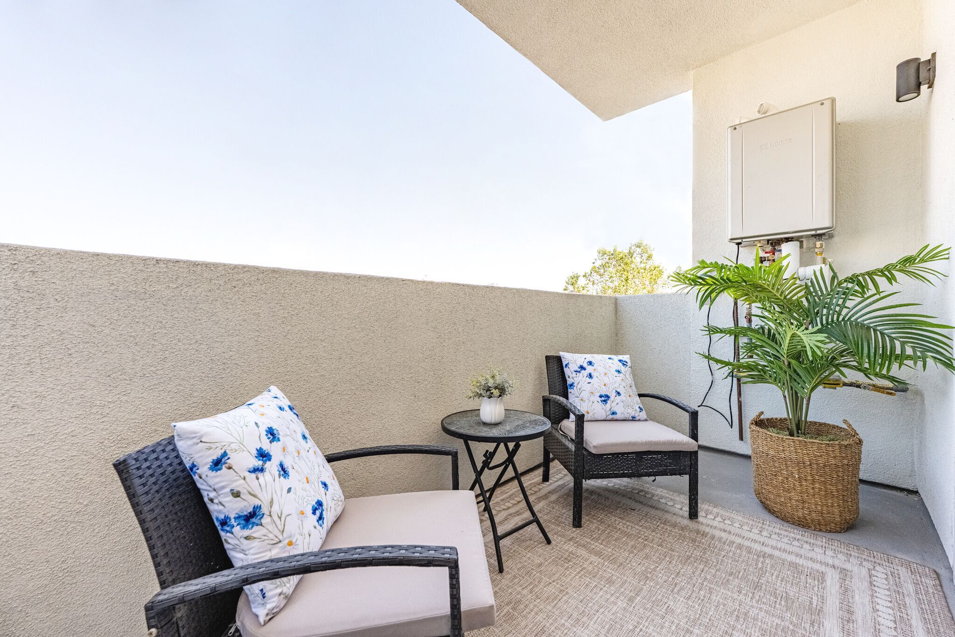 The balcony showing 2 couches, coffee table and plant in a unit at The Secret at K-Town Luxury Apartments in Los Angeles