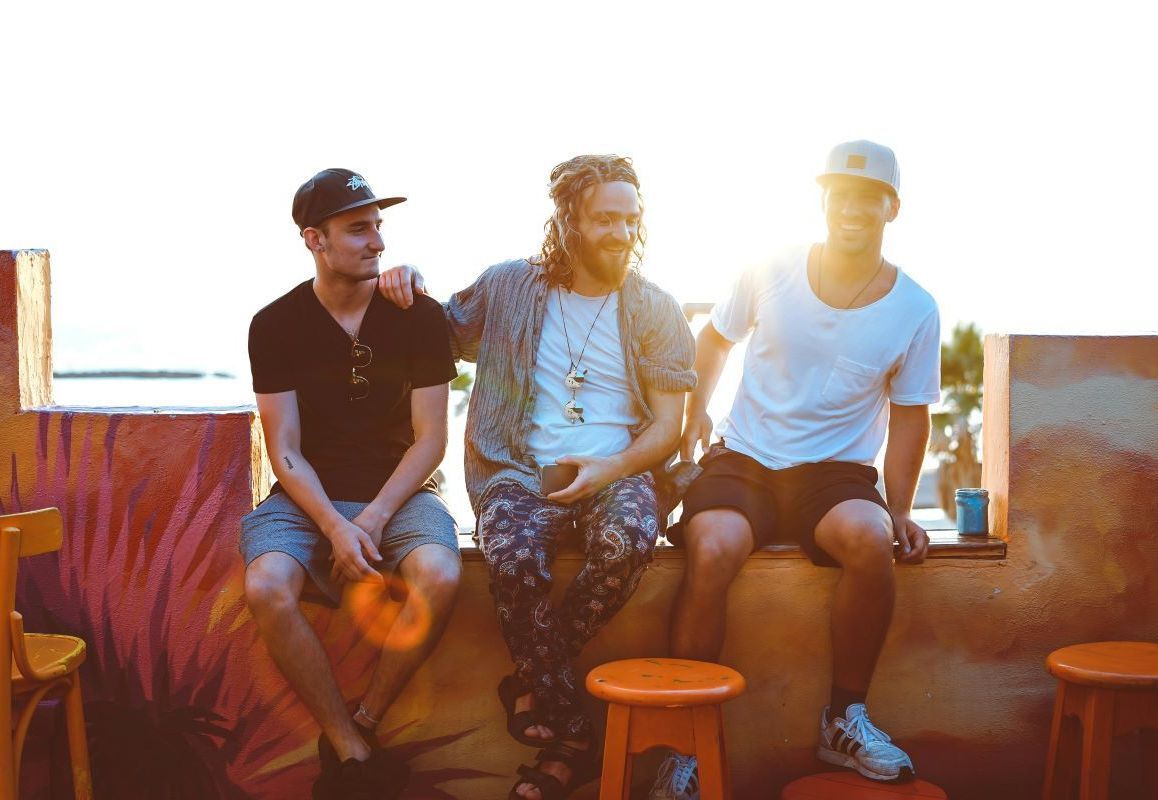 photo of three men happily chatting on an apartment rooftop 