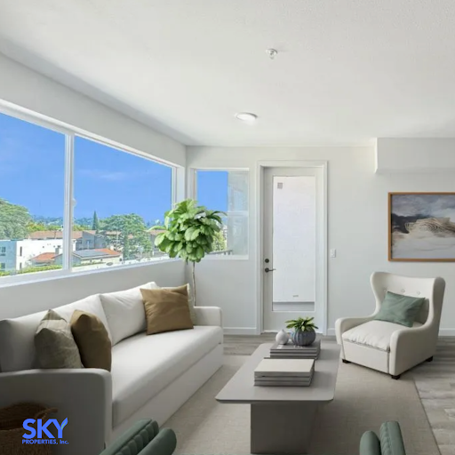 Bright, modern living room with an overlooking view of clear skies, buildings, and greenery. 