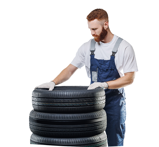 A man is standing next to a pile of tires. | Oceanside Tire and Service Center Tire Pros