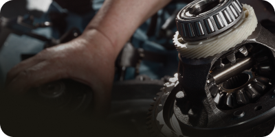 A person is working on a gearbox in a car. | Oceanside Tire and Service Center Tire Pros