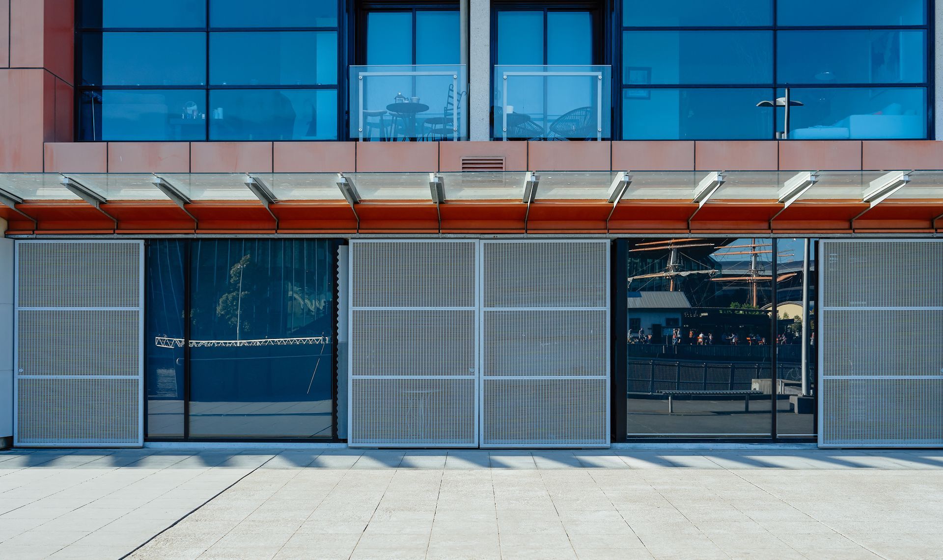 A brick road and the front of an office building full of windows during the day.