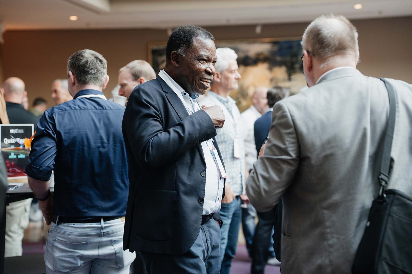 Eine Gruppe von Männern steht in einem Raum und unterhält sich miteinander.