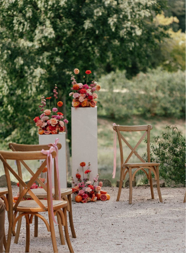 Une table dressée pour une réception de mariage avec des assiettes, des verres, des serviettes et un vase de fleurs dessus.