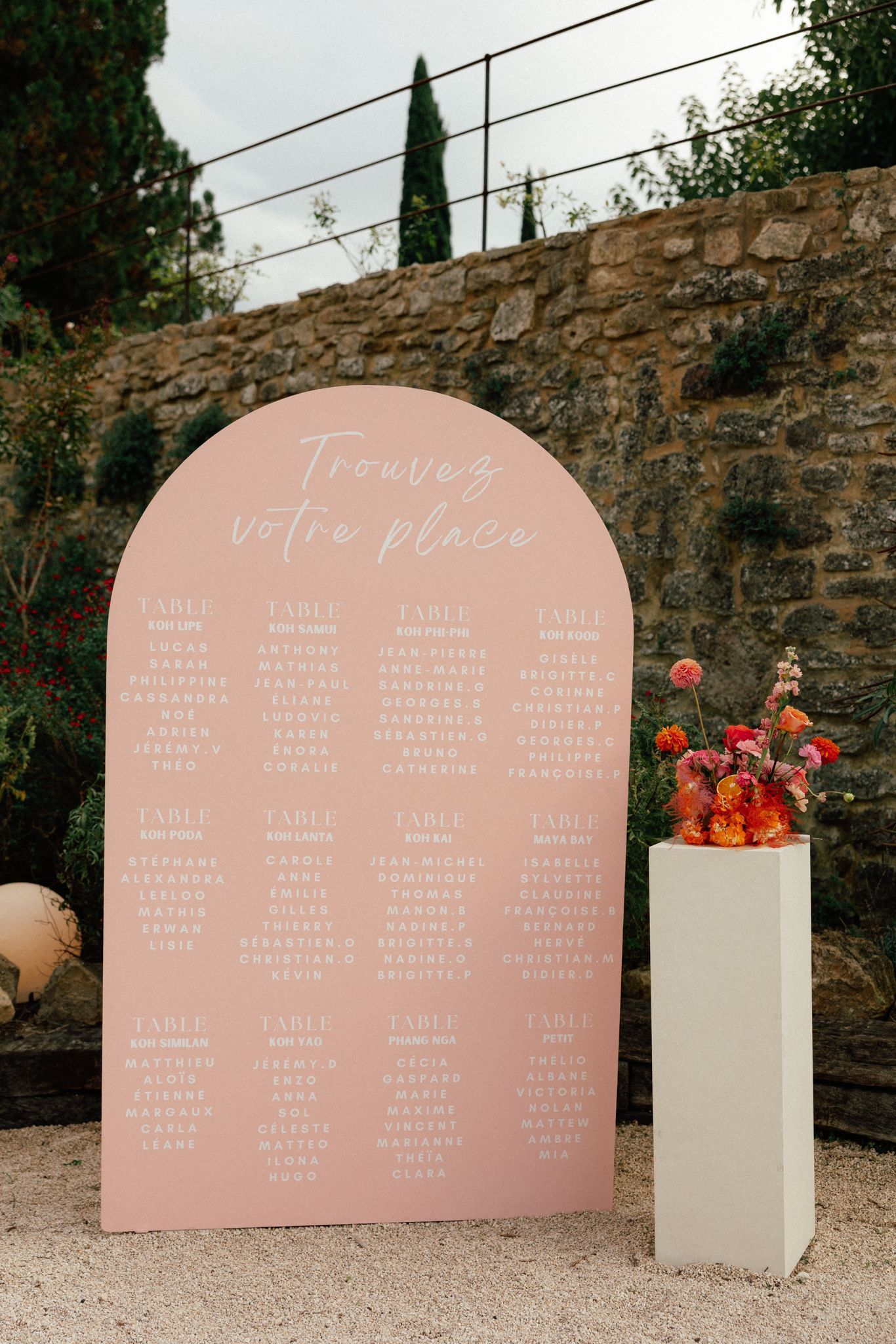 Un grand miroir avec un cadre doré est entouré de vases de fleurs