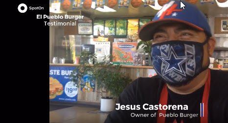 A man wearing a mask and a hat is sitting in a restaurant.