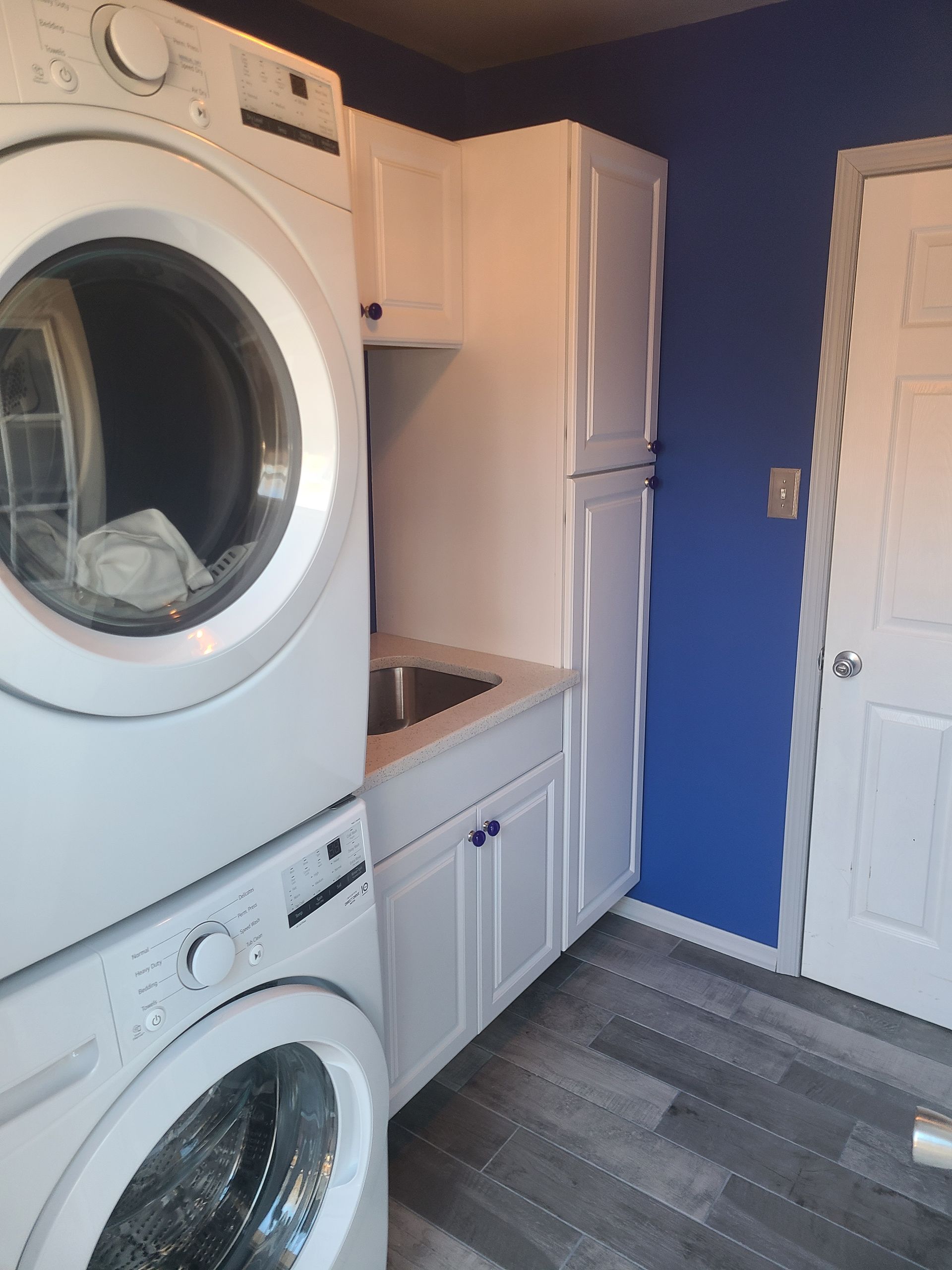 Spacious room with hardwood floors, detailed trim, windows, and a dark wood front door.