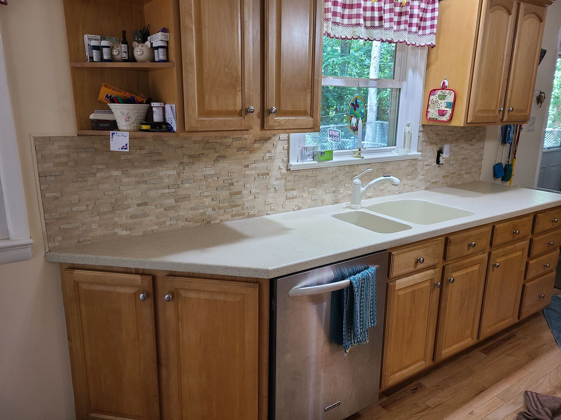 White kitchen with island, built-in appliances, and herringbone wood floors; large windows and open doors.