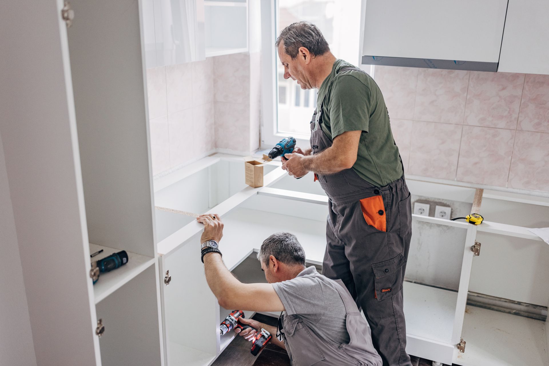 Construction worker installing black rain gutter on wooden roof.