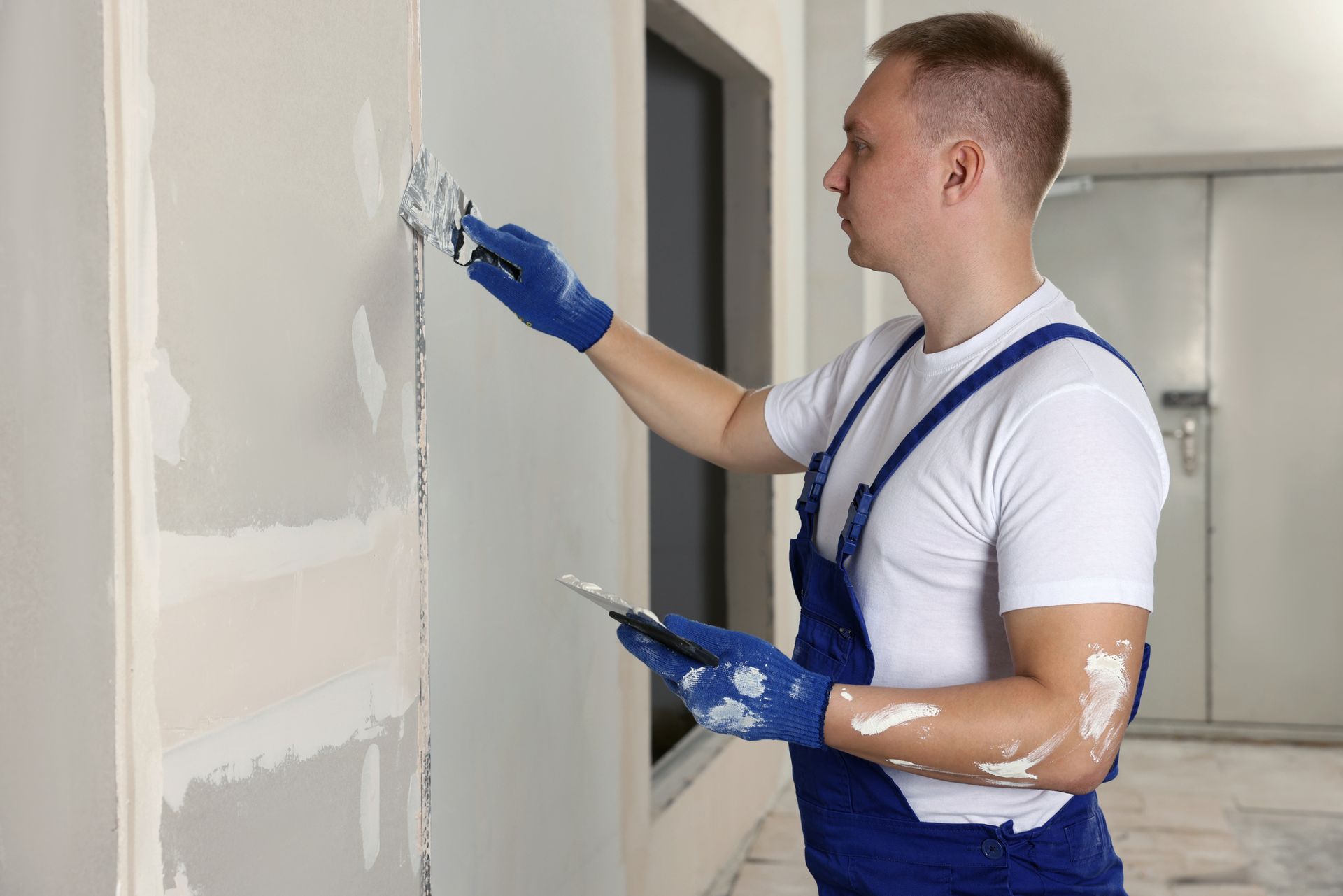Aerial view of a backyard with green grass, a white fence, patio, and a tree.