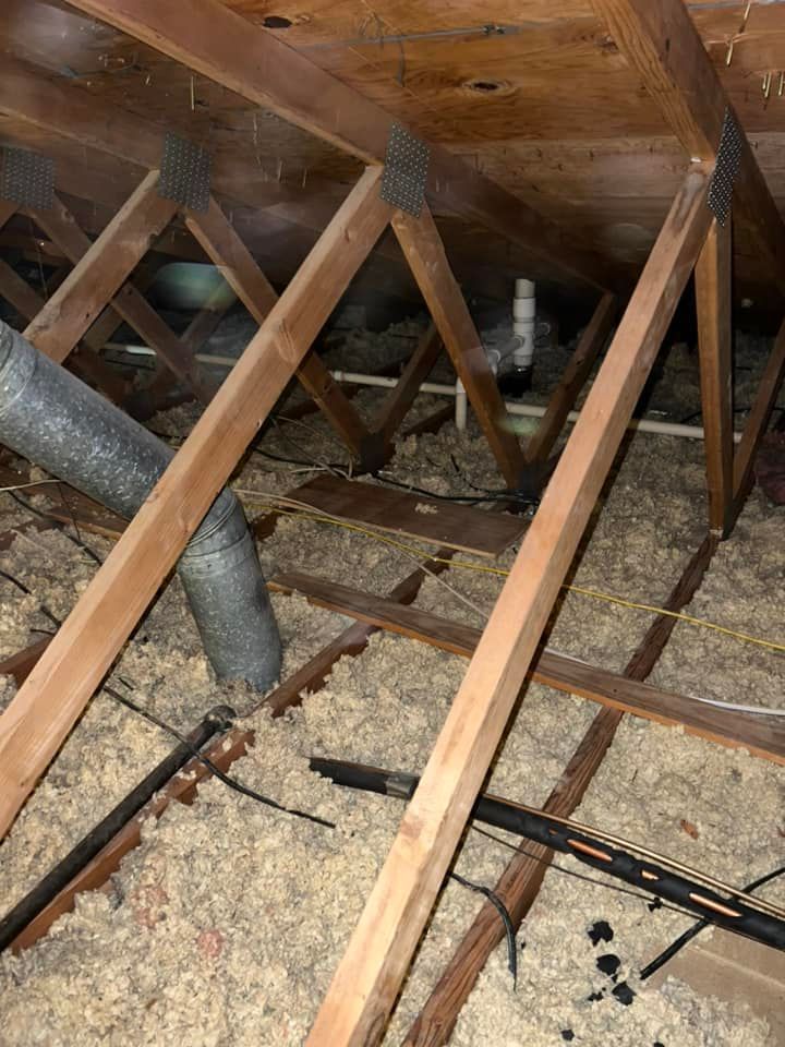 The ceiling of an attic with wooden beams and insulation.