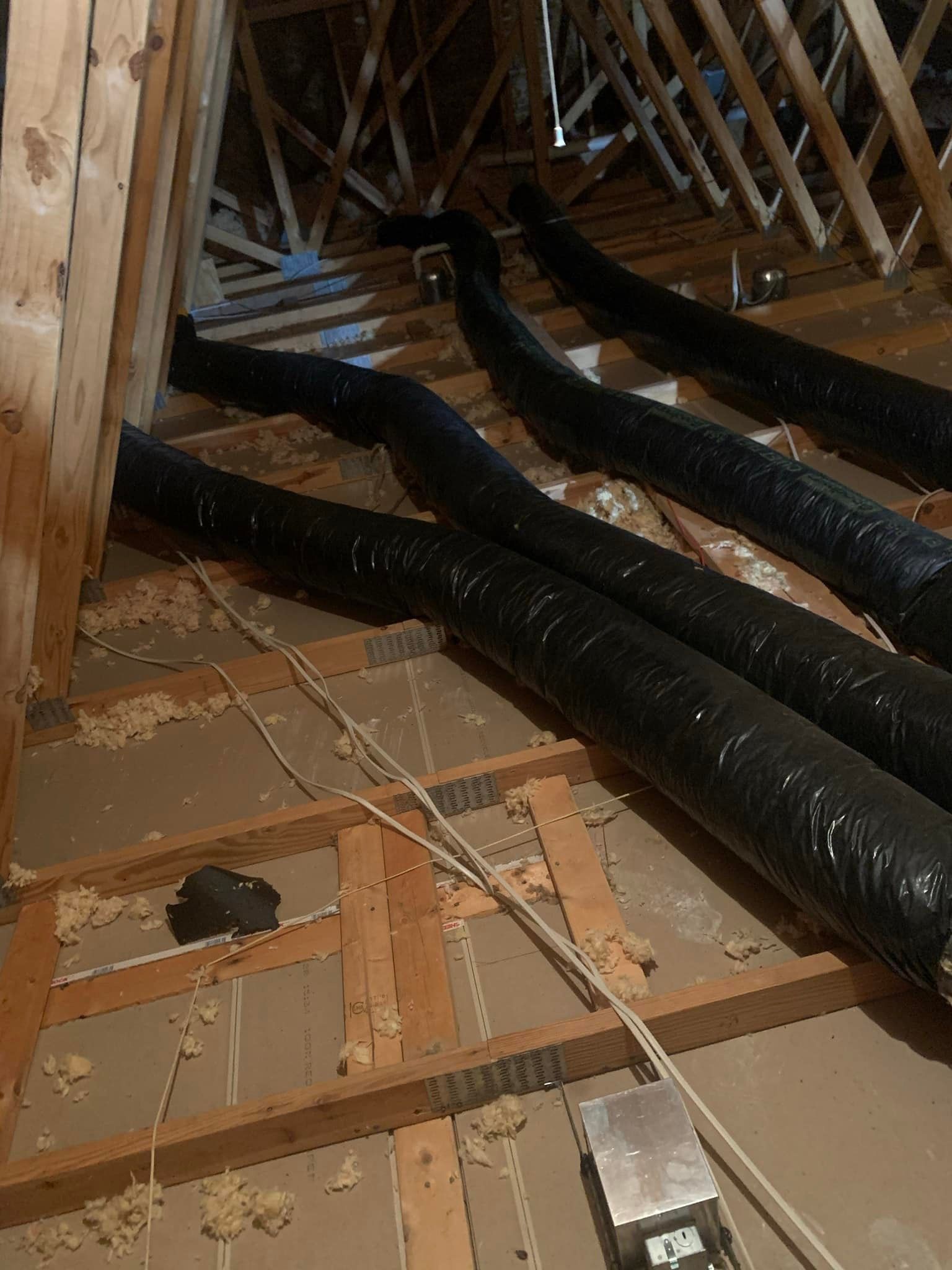 A bunch of black pipes are laying on the floor of a building.