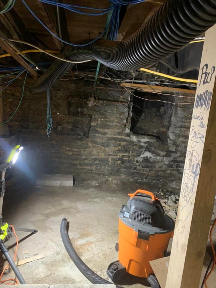 A vacuum cleaner is sitting in a basement next to a wooden post.