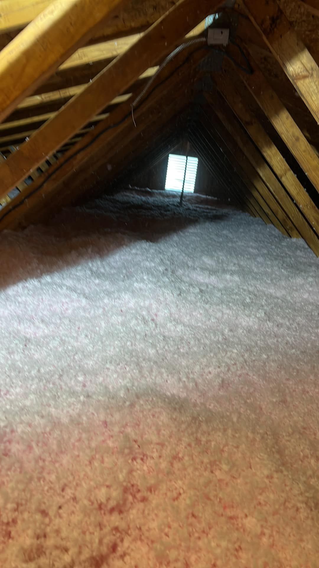 The attic is filled with insulation and a window.