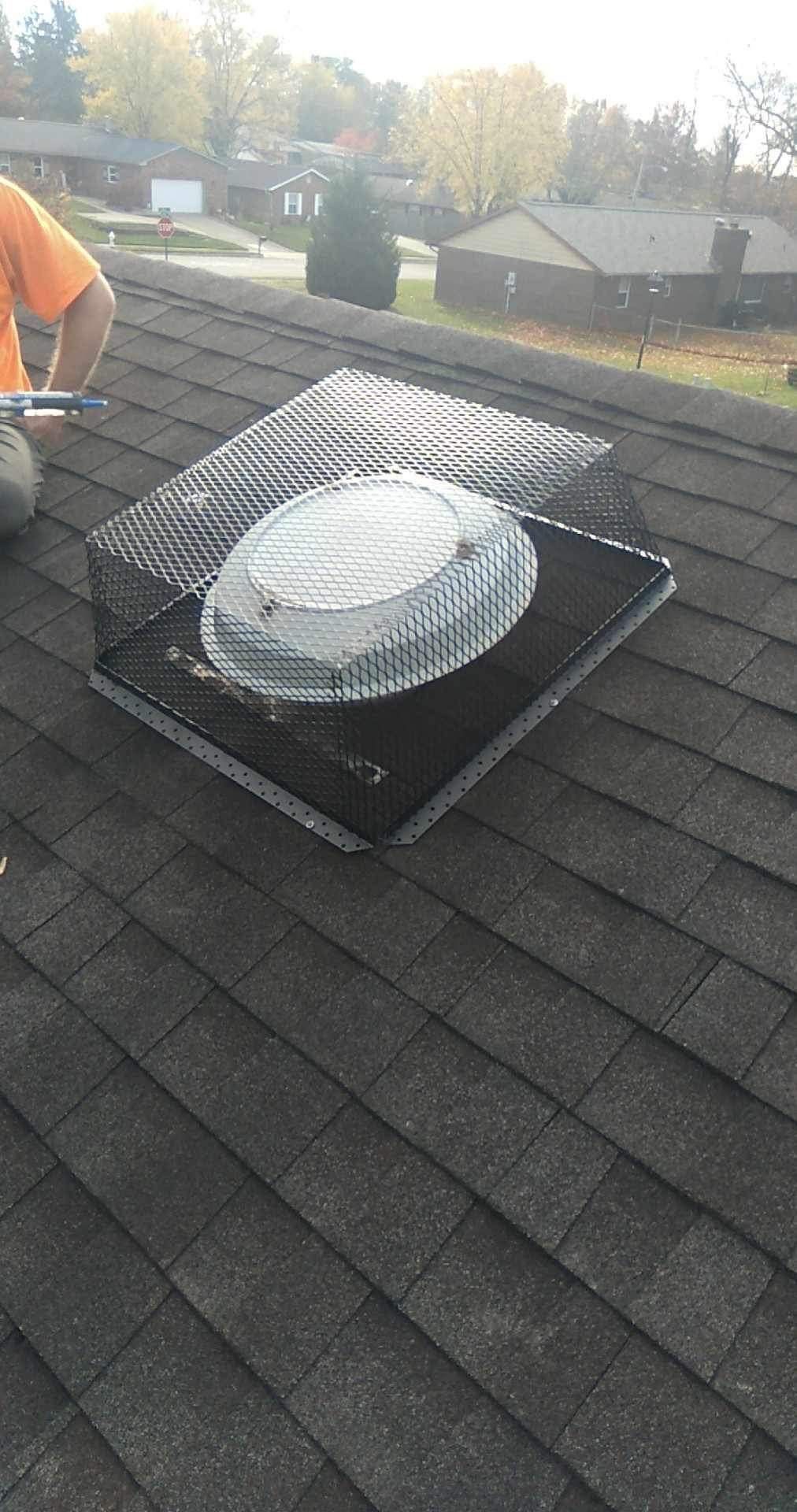 A man is working on a roof with a fan.
