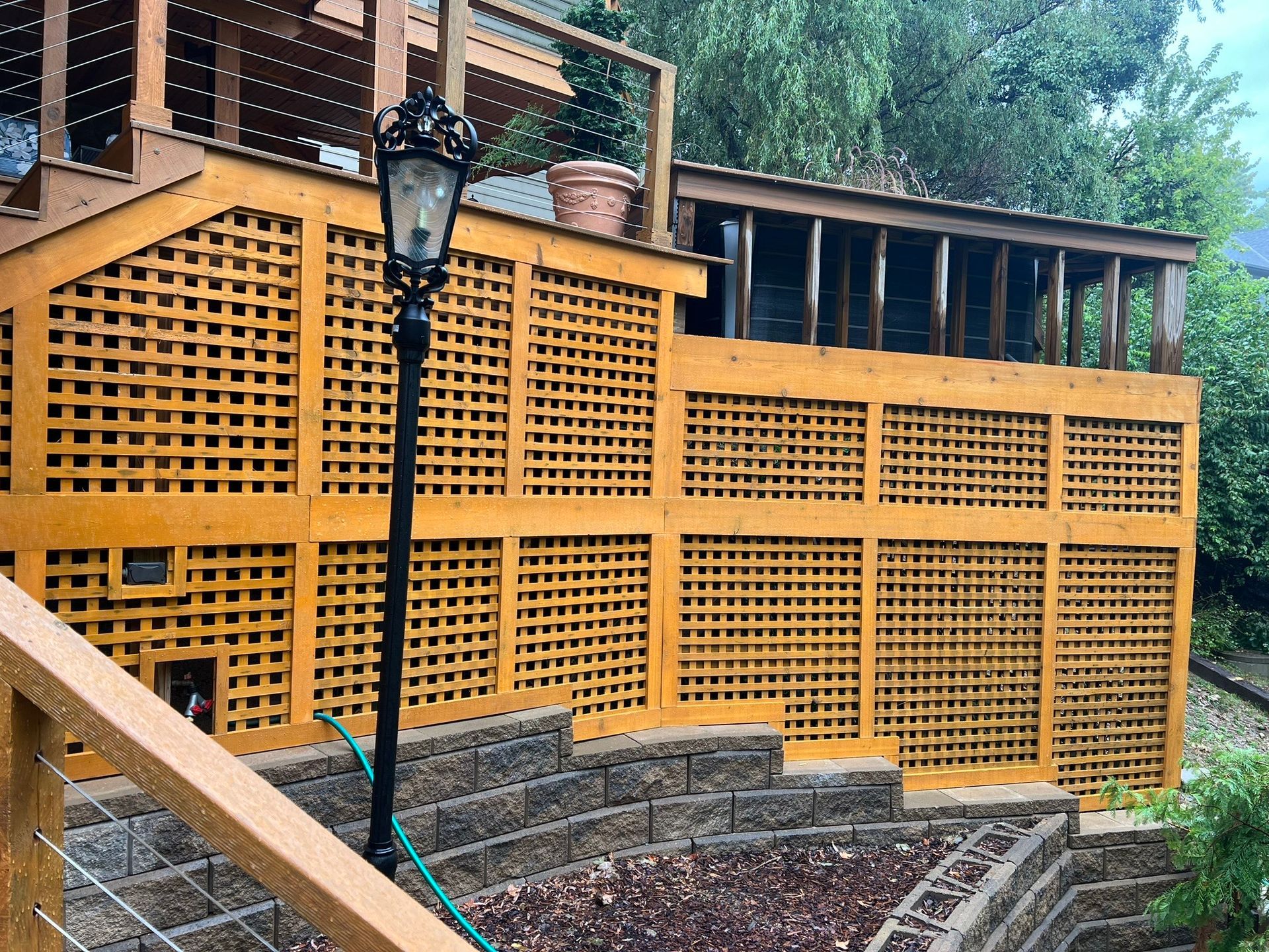 A wooden deck with stairs leading up to it and a lamp post in front of it.