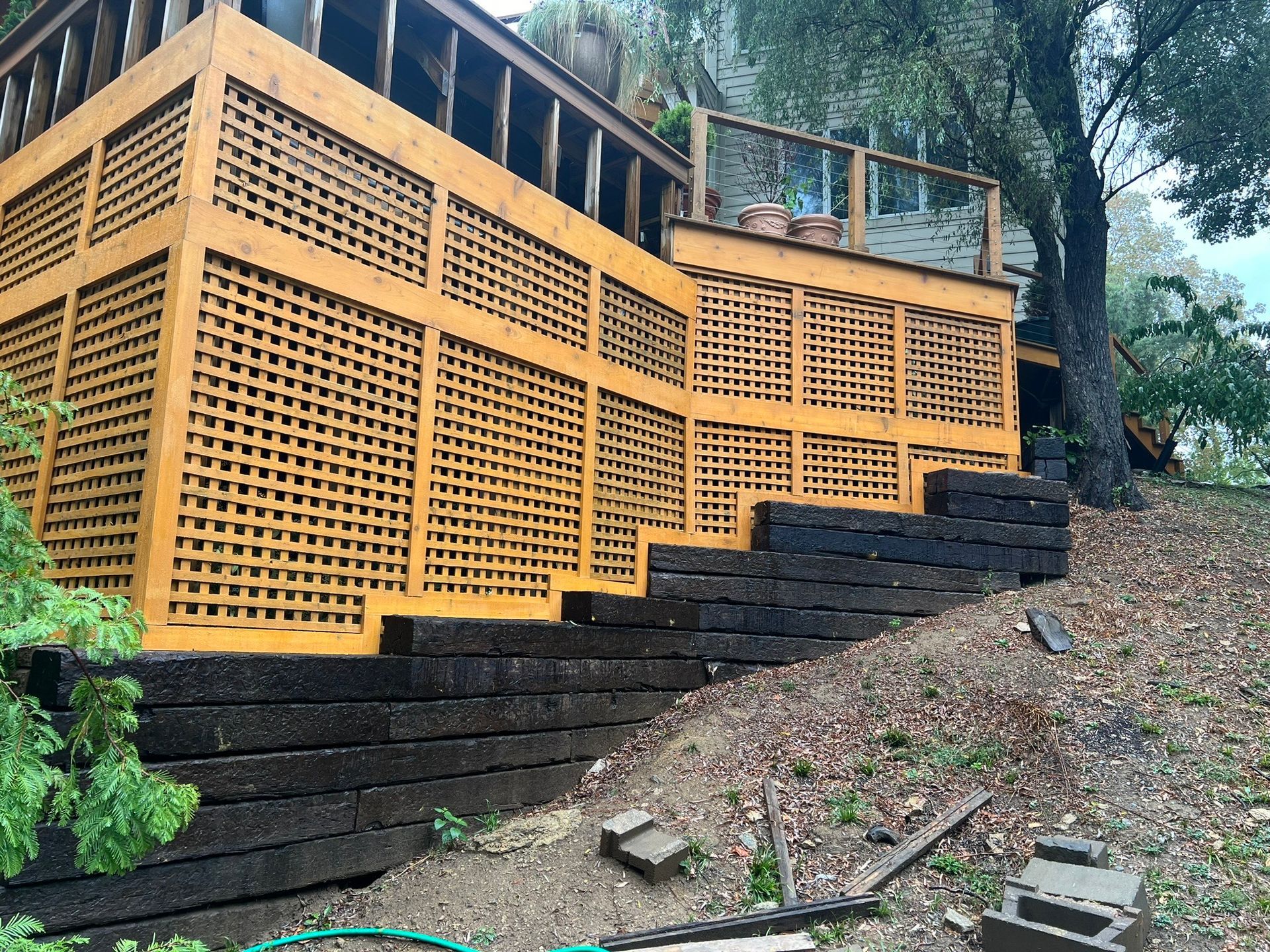 A wooden deck with stairs leading up to it is sitting on top of a hill.