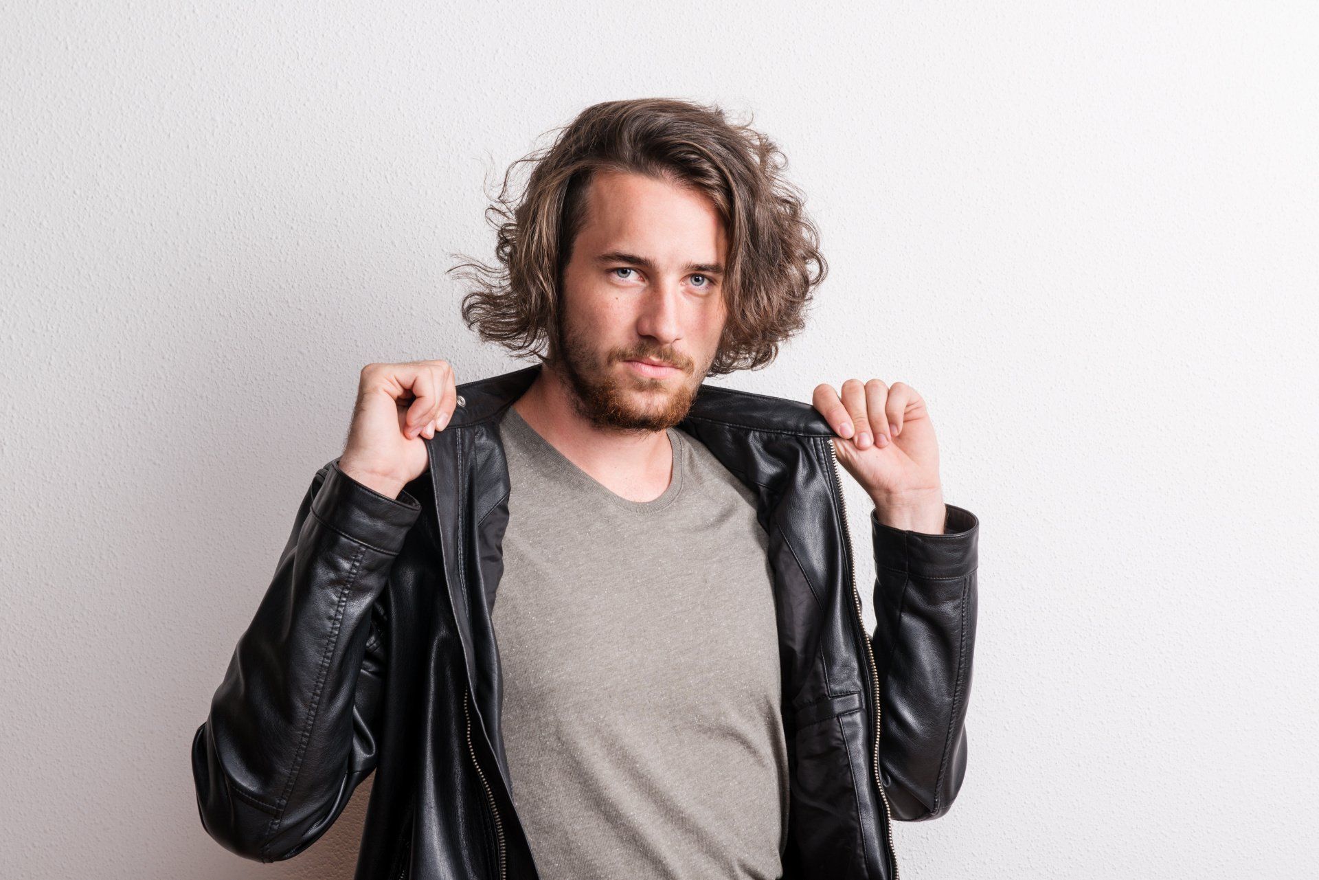 Portrait of a young man with black jacket in a studio.