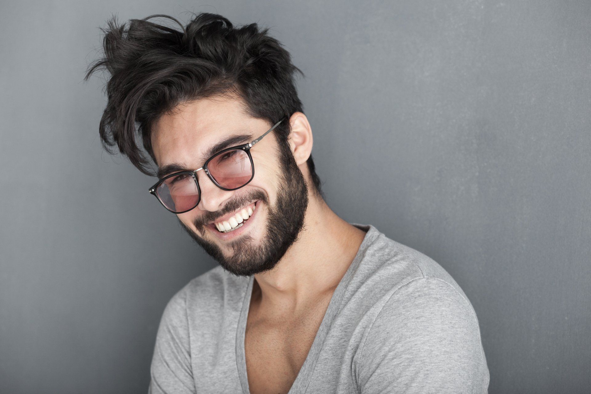 sexy man with beard smiling big against wall