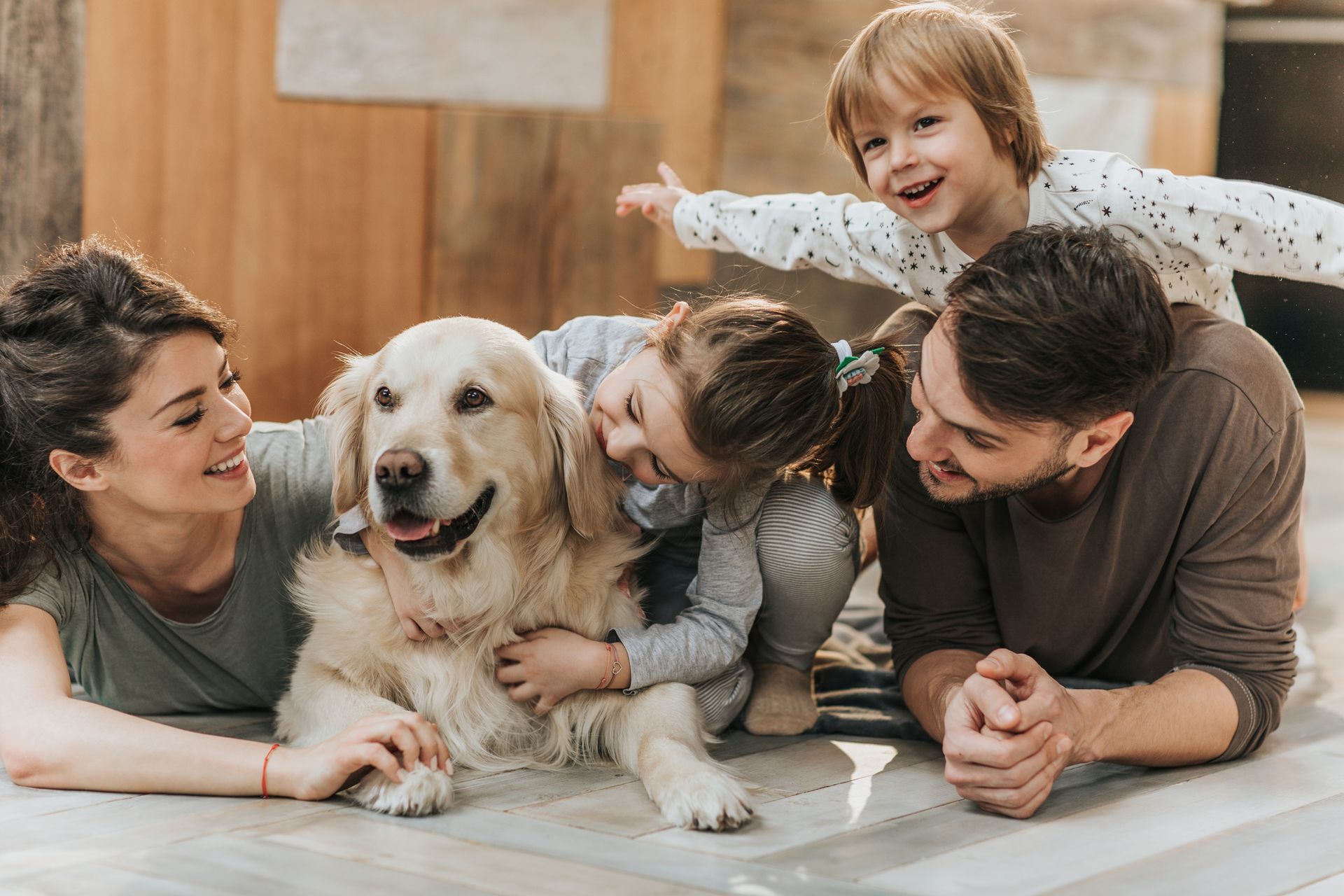 A family is laying on the floor with a dog.