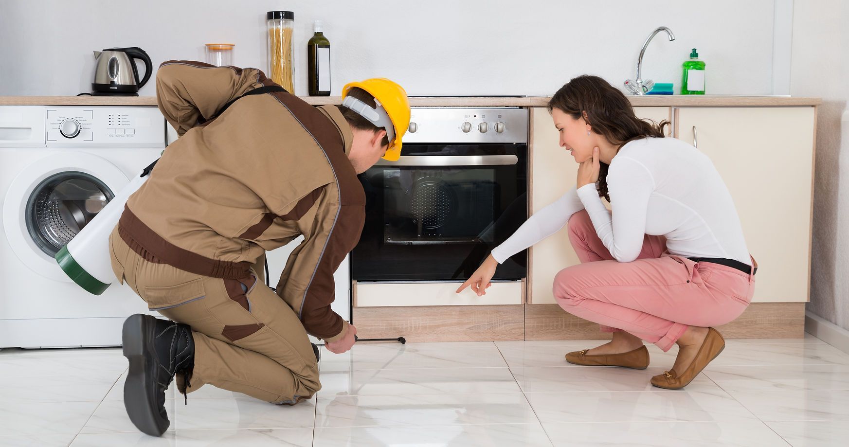 A man and a woman are looking at an oven in a kitchen.