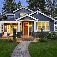 A large blue and white house with a brick walkway leading to it.