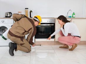 A man and a woman are looking at a bug in a kitchen.