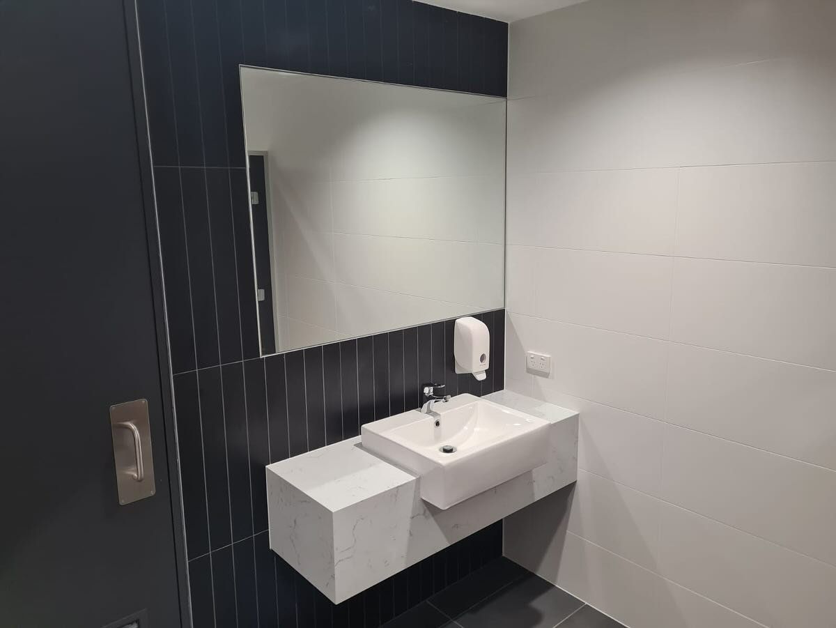 Bathroom With A Floating Sink, Mirror, And A Dark Tiled Wall — Zeal Interiors in South Grafton, NSW