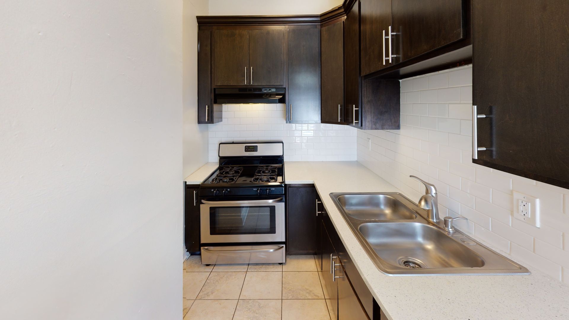 Kitchen with dark cabinets, stainless steel appliances, and white countertops.