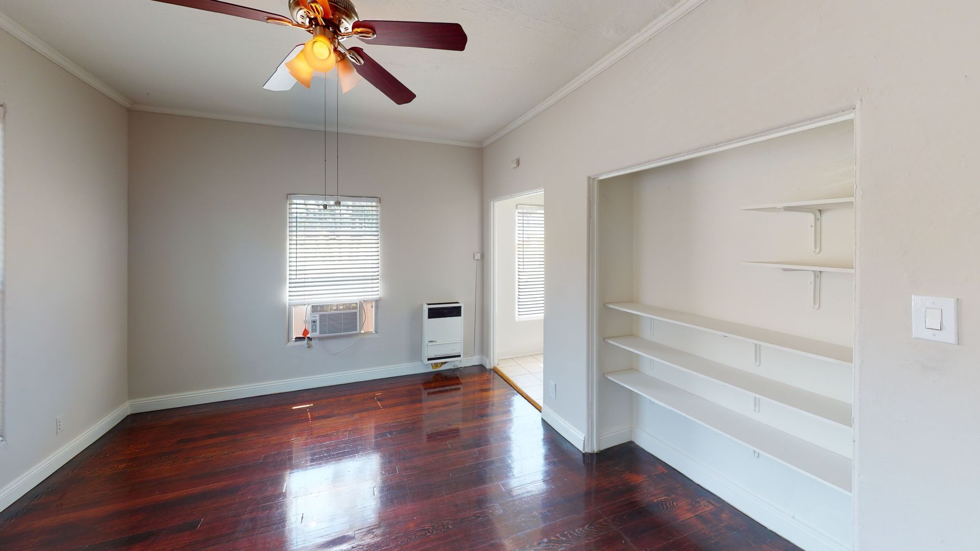 Empty room with hardwood floors, closet, window, and ceiling fan.